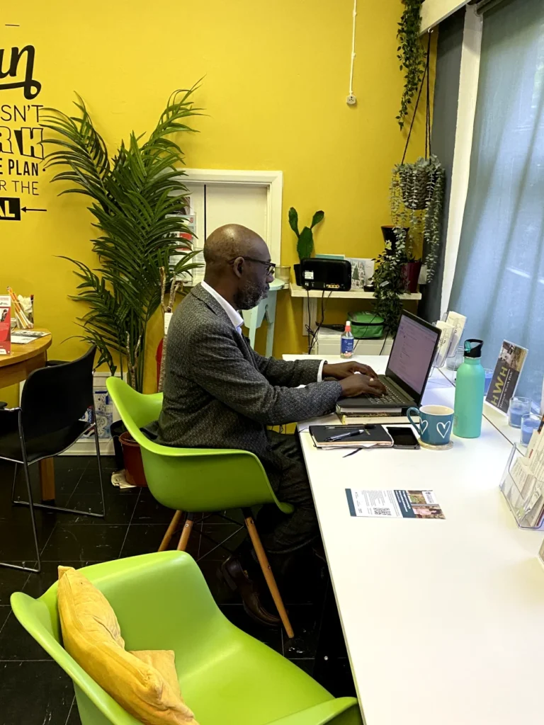 Entrepreneur working at laptop in bright yellow co-working room