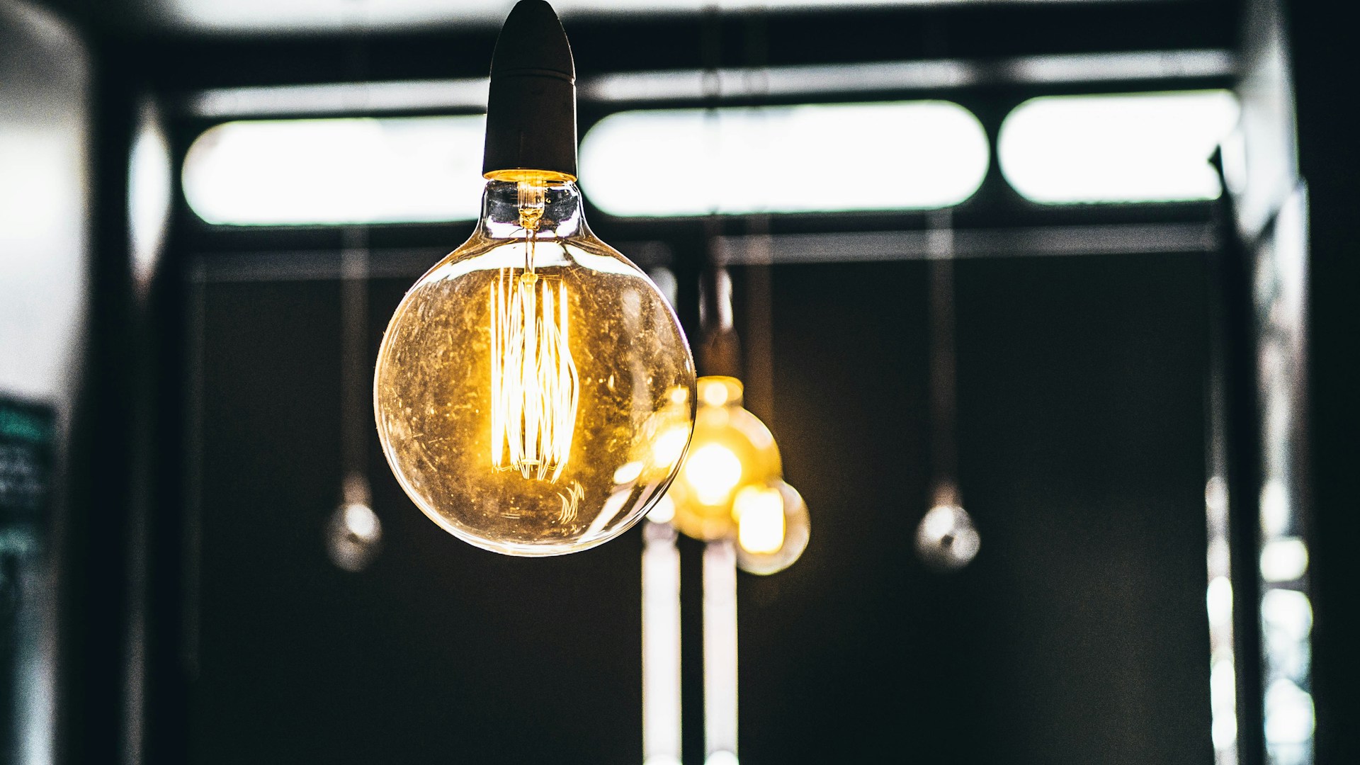 A round light bulb - the coil is lit up. The bulb is handing from an industrial style fixture.