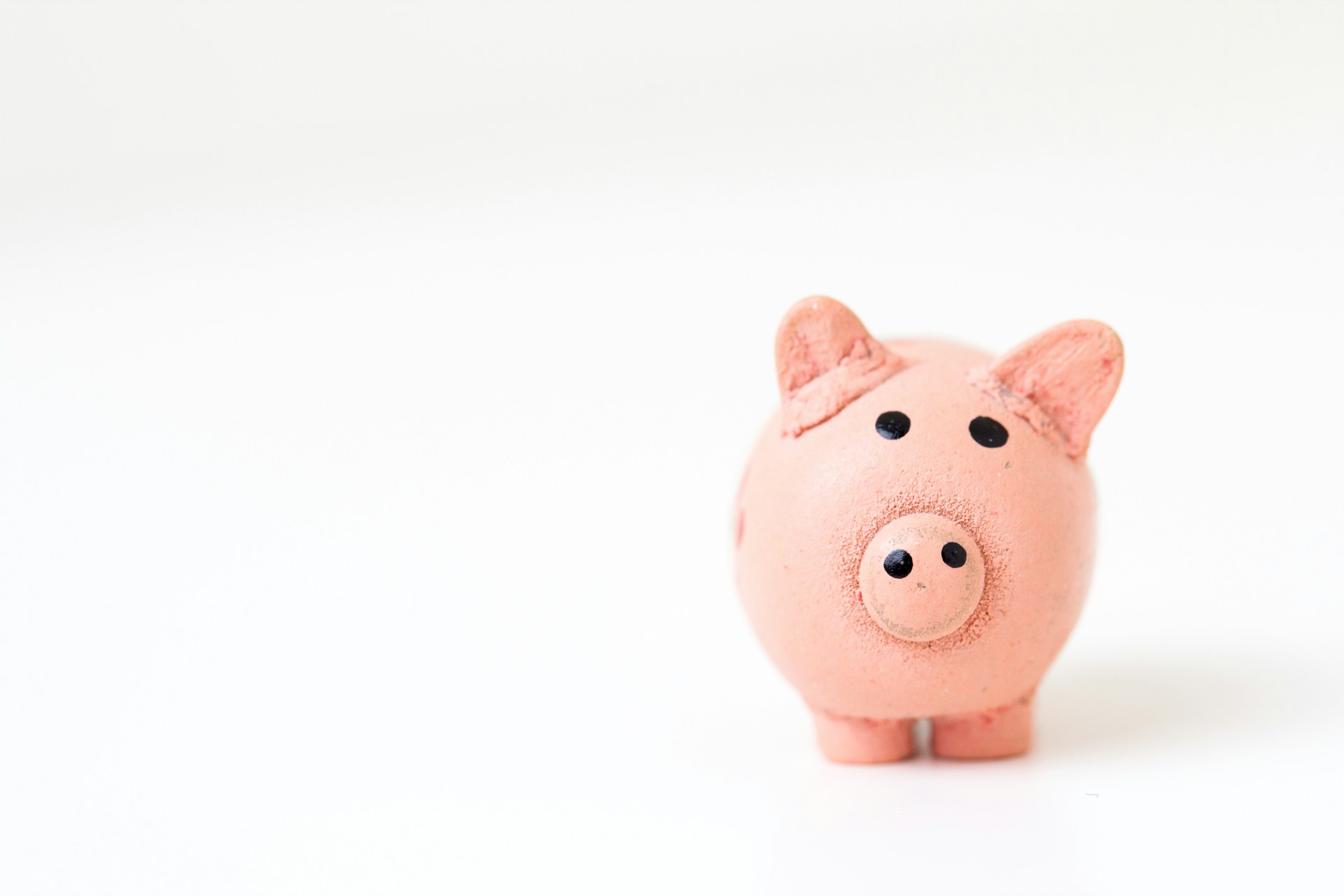 a cute pink piggy banks stands on a white surface with a white background